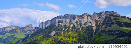 Majestic mountain range under a bright blue sky with green valleys in the foreground during daytime 130934401
