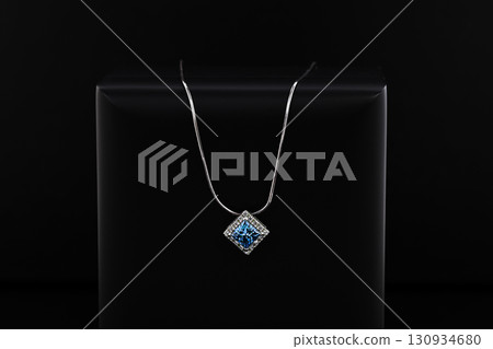 A blue and white necklace sits on a black surface 130934680