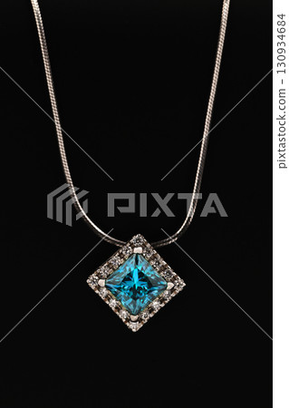 A blue diamond necklace sits on a black surface 130934684