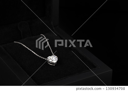 A heart shaped pendant with a chain is displayed in a black box 130934708