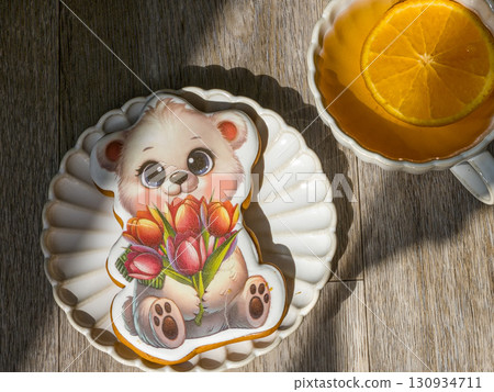 Sunlit orange tea with gingerbread bear cookie on plate. High quality photo Sunlit orange tea with gingerbread bear cookie on plate. High quality photo 130934711