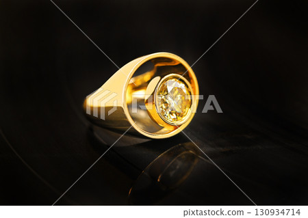 A gold ring with a yellow stone in the center 130934714