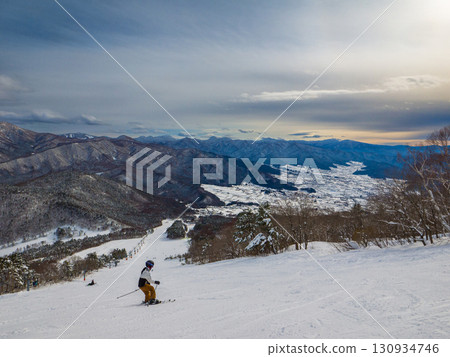 一位孤獨的滑雪者在壯麗的風景中滑雪，俯瞰著白雪皚皚的山脈（長野縣山之內町，夜瀨町） 130934746