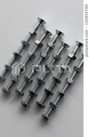 Nuts On A Long Screw Bolts On White Surface Top View Textured Background  130934780