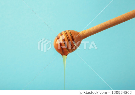 Wooden honey dipper with dripping honey on blue background 130934863