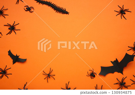 Halloween background with spiders as symbols of Halloween on orange background. Space for text 130934875