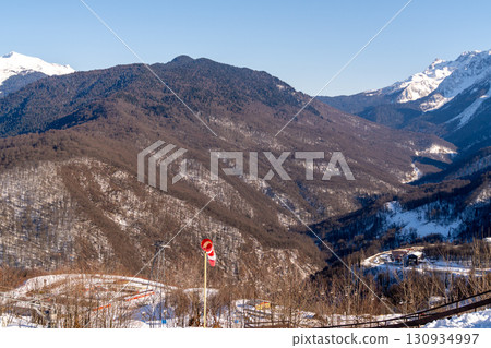 Mountains Caucasus Winter Flag: Scenic panorama showcasing snowy Caucasus Mountains with a flag, likely marking a location, during winter. Mountains Caucasus Winter Flag: Scenic panorama showcasing snowy Caucasus Mountains with a flag, likely marking a location, during winter. 130934997