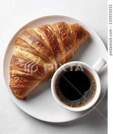 A steaming cup of coffee next to a butter croissant A steaming cup of coffee next to a butter croissant 130935032