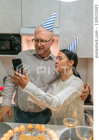 Couple Birthday Celebration Selfie Kitchen: Happy couple takes selfie with birthday cake during kitchen party. Couple Birthday Celebration Selfie Kitchen: Happy couple takes selfie with birthday cake during kitchen party. 130935083