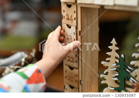 A child opens wooden advent calendar with presents 130935097