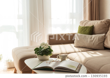 Cozy Living Room with Coffee, Book and African Violet on Table Cozy Living Room with Coffee, Book and African Violet on Table 130935193