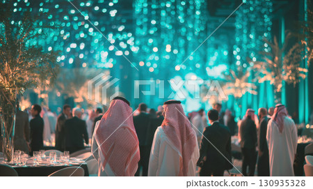 Two men in traditional headdresses, white robes stand in decorated hall. The backdrop is a festive, blurred array of sparkling blue and white lights, suggesting a luxurious celebration, special event 130935328