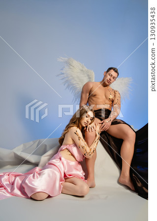 Couple embracing in elegant attire with angelic theme and soft background 130935438