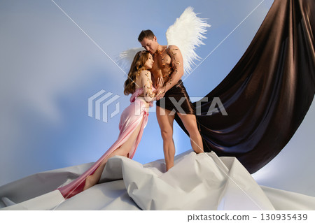 Couple posing as angel and goddess against a stylistic backdrop 130935439