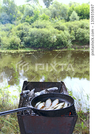Cooking fresh caught fish. Successful fishing. Delicious fish dish fried on fire Cooking fresh caught fish. Successful fishing. Delicious fish dish fried on fire 130935697