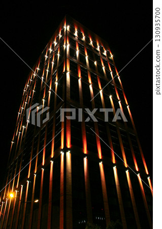 Beautiful illumination on modern skyscraper in night city. illuminated building Beautiful illumination on modern skyscraper in night city. illuminated building 130935700