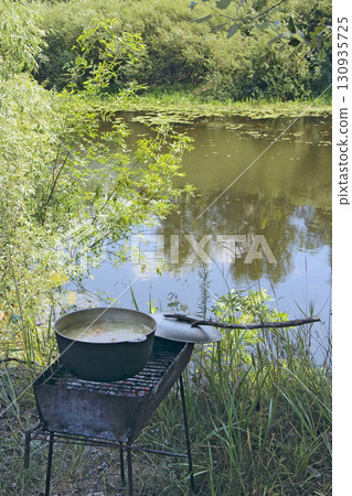 Soup is cooked in pot near the river. Cooking in nature. Cooked food 130935725