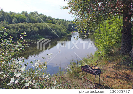 Cooking meat on river bank. Frying pieces of meat. Delicious dish fried on pan 130935727