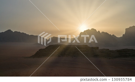 Sunrise over a serene desert landscape with mountains in the distance 130935784