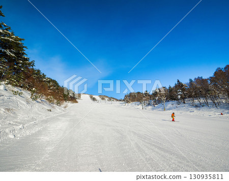 Skiers skiing down the groomed slopes of a ski resort in the morning (Yamanouchi Town, Nagano Prefecture, Yomase) 130935811