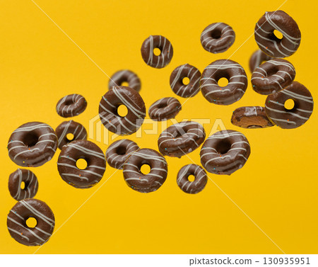 Dynamic composition with chocolate donuts in glaze that fall or float in the air. Yellow background 130935951