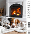 A dog is relaxing on a cozy blanket next to a fireplace on a cool day. 130936174