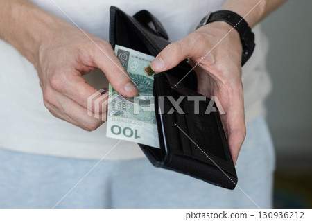 Man holding a black wallet with 100 Polish zloty. Closeup. Man holding a black wallet with 100 Polish zloty. Closeup. 130936212