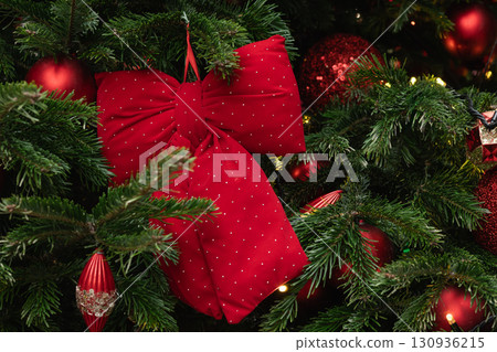 Christmas tree decorated red trendy bow and lights garland. Xmas card. Winter holiday spirit. Outdoors. Christmas tree decorated red trendy bow and lights garland. Xmas card. Winter holiday spirit. Outdoors. 130936215