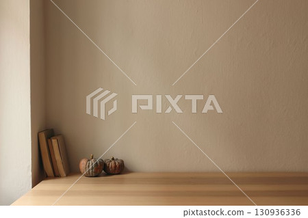 Autumn interior still life. Scandinavian living room, home office. Pumpkins, old books on table, desk. Fall, Halloween or Thanksgiving holiday home decor. Empty beige wall mockup background. 130936336