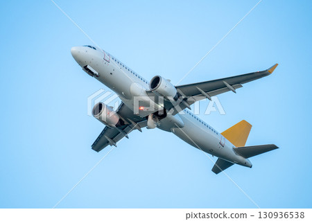 Passenger airplane flight in blue sky bottom view. Travel concept. 130936538