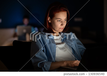 Woman uses laptop, works, studies. Overwork until late in evening, fatigue, hard study 130936540