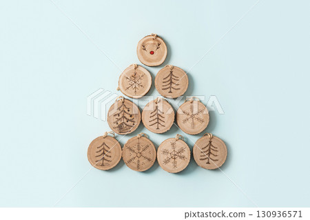 Alternative Christmas tree made of wooden slice with burn ornament on blue background. DIY. Nature material. Xmas card. Eco friendly. View from above. 130936571