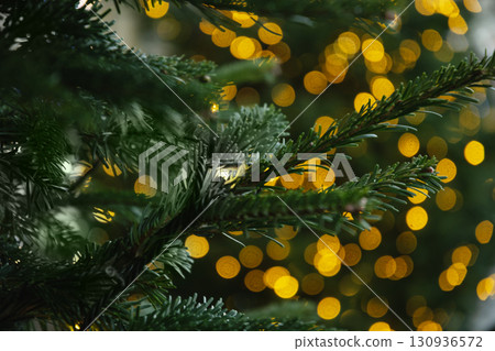 Blurred Christmas tree with golden lights garland. Abstract pattern. Defocused background. Xmas holiday spirit. Blurred Christmas tree with golden lights garland. Abstract pattern. Defocused background. Xmas holiday spirit. 130936572