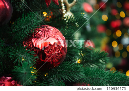 Christmas tree with red ball and lights garland. Xmas card. Close up. Winter holiday spirit. Outdoors. Christmas tree with red ball and lights garland. Xmas card. Close up. Winter holiday spirit. Outdoors. 130936573