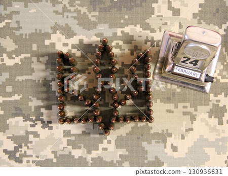 Coat of arms of Ukraine laid out from cartridges on camouflage clothing Coat of arms of Ukraine laid out from cartridges on camouflage clothing 130936831