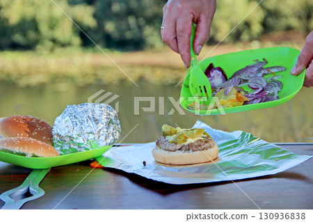Cooking burger outdoors. Outdoor food. Woman making hamburger 130936838