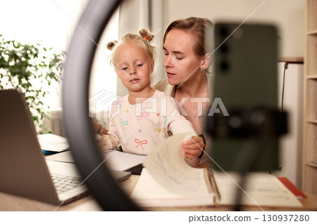Mother assisting young daughter with remote learning at home workplace setup Mother assisting young daughter with remote learning at home workplace setup 130937280