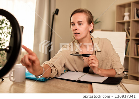 Professional woman conducting an online conference from her modern home workspace Professional woman conducting an online conference from her modern home workspace 130937341