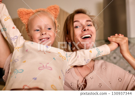 Happy mother and daughter sharing joyful moments with playful expressions Happy mother and daughter sharing joyful moments with playful expressions 130937344