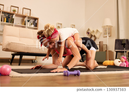 Mother and daughter exercising together at home in a joyful atmosphere 130937383