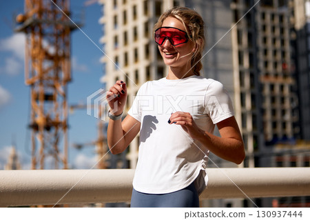 Woman jogging outdoors in the city wearing stylish sporty sunglasses Woman jogging outdoors in the city wearing stylish sporty sunglasses 130937444