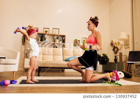 Mother and daughter exercise together at home with dumbbells and enthusiasm 130937452