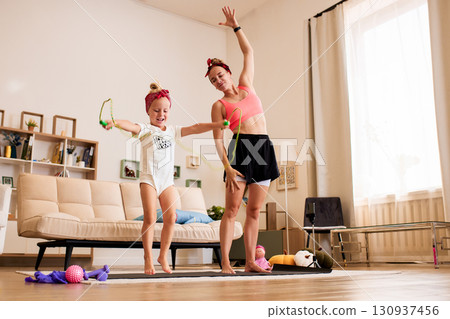 Mother and daughter exercising together during a home fitness session 130937456
