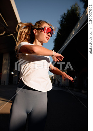 Sprightly woman working out outdoors in casual fitness attire during sunset Sprightly woman working out outdoors in casual fitness attire during sunset 130937691