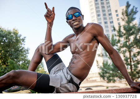 Athletic man posing outdoors with sunglasses in an urban environment Athletic man posing outdoors with sunglasses in an urban environment 130937728