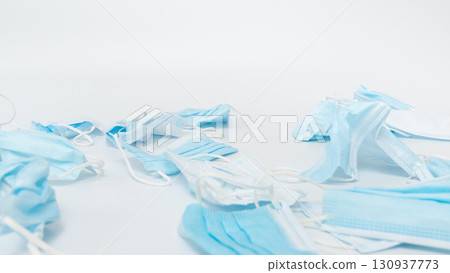 Discarded medical face masks scattered on a clean surface, showcasing various shades of blue and white, emphasizing the environmental impact of single-use protective equipment in healthcare settings Discarded medical face masks scattered on a clean surface, showcasing various shades of blue and white, emphasizing the environmental impact of single-use protective equipment in healthcare settings 130937773