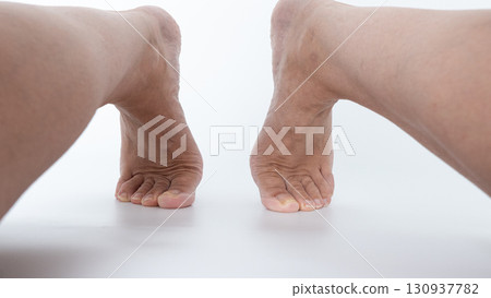 Close-up view of two bare feet positioned apart on a smooth surface, showcasing natural skin texture and relaxed posture in a serene setting 130937782