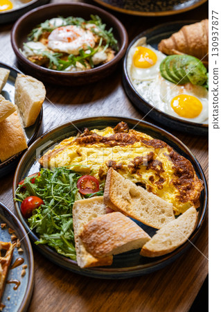 Healthy breakfast with omelet, ciabatta, salad and tea on dark stone background 130937877