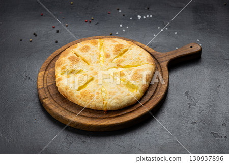 Traditional Imeruli khachapuri flatbread filled with cheese, on a wooden serving board 130937896