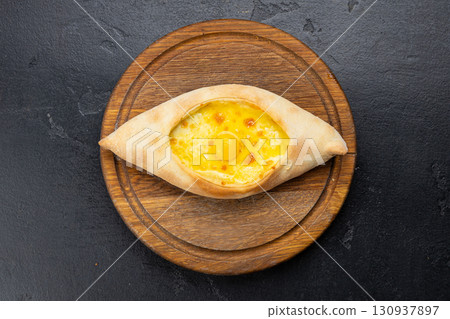 Traditional Georgian Adjarian khachapuri with eggs and cheese on a wooden board 130937897